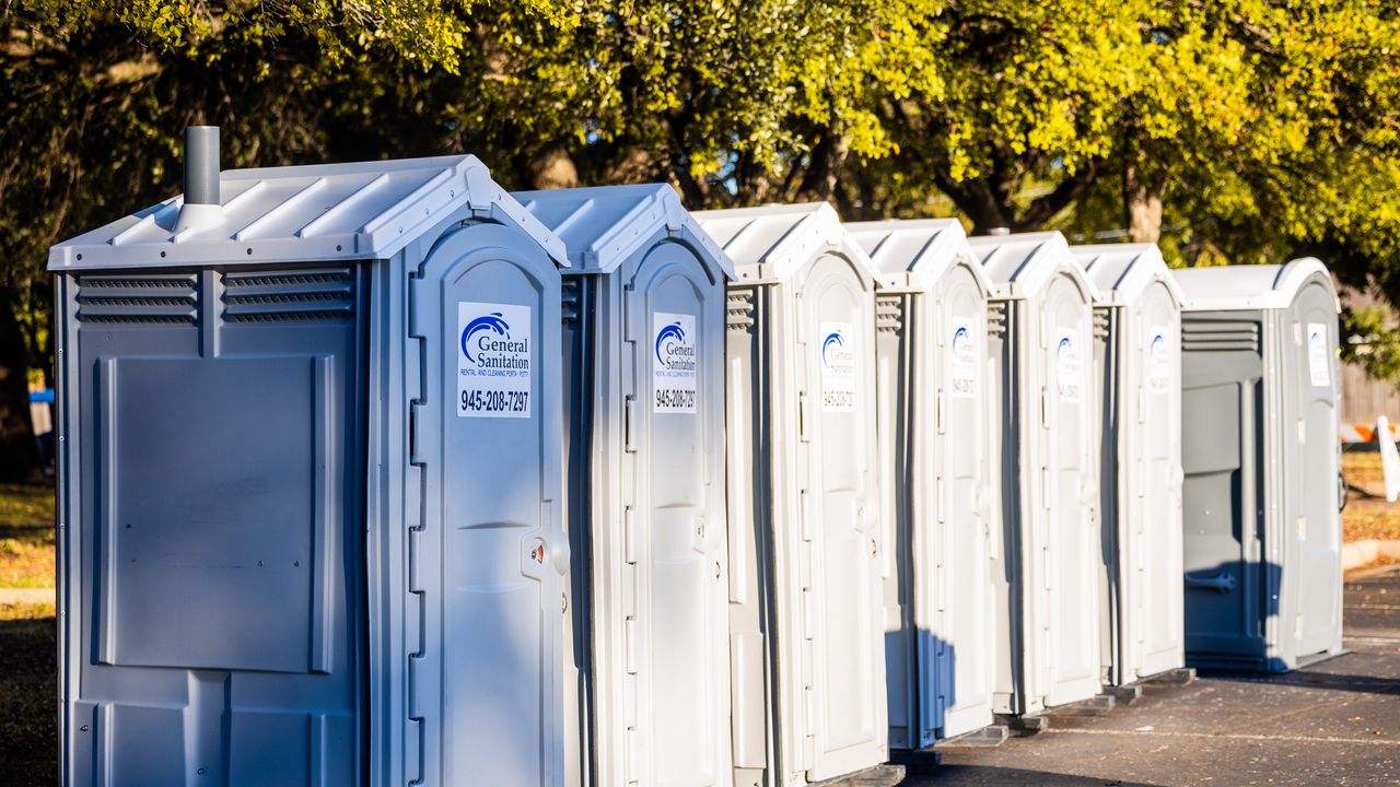 Fileira de banheiros portáteis instalados ao ar livre em uma área de camping