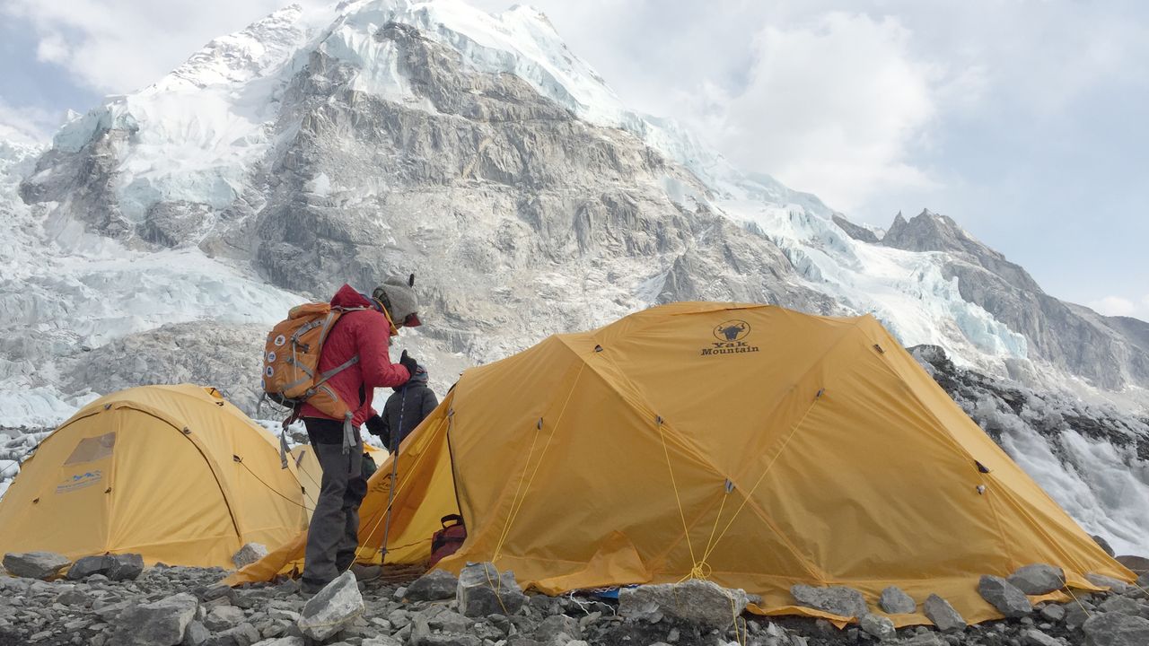 Barracas de expedição montadas em acampamento na neve com montanhas ao fundo