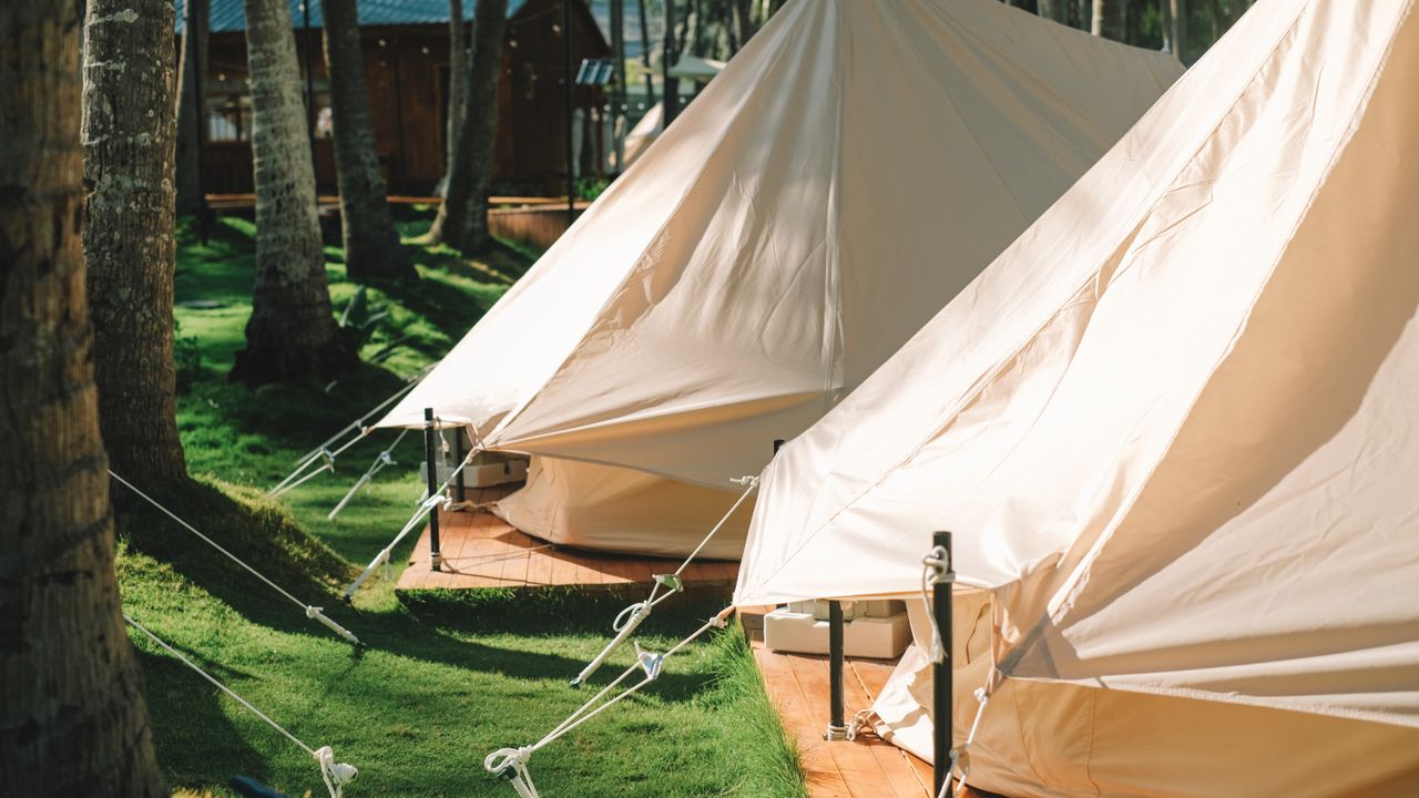 Barraca de camping com varanda e toldo montada em meio à natureza, sobre deck de madeira