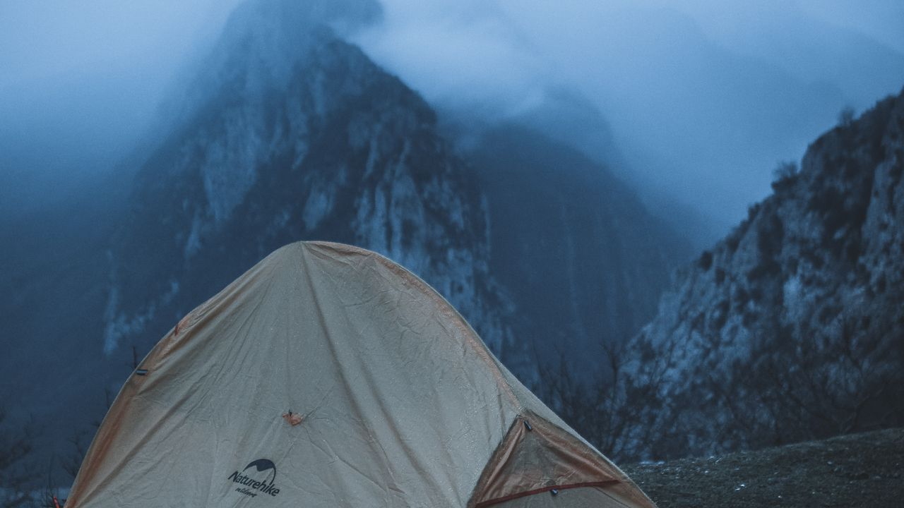 Barraca de camping montada em área verde, com avanço e equipamentos na varanda