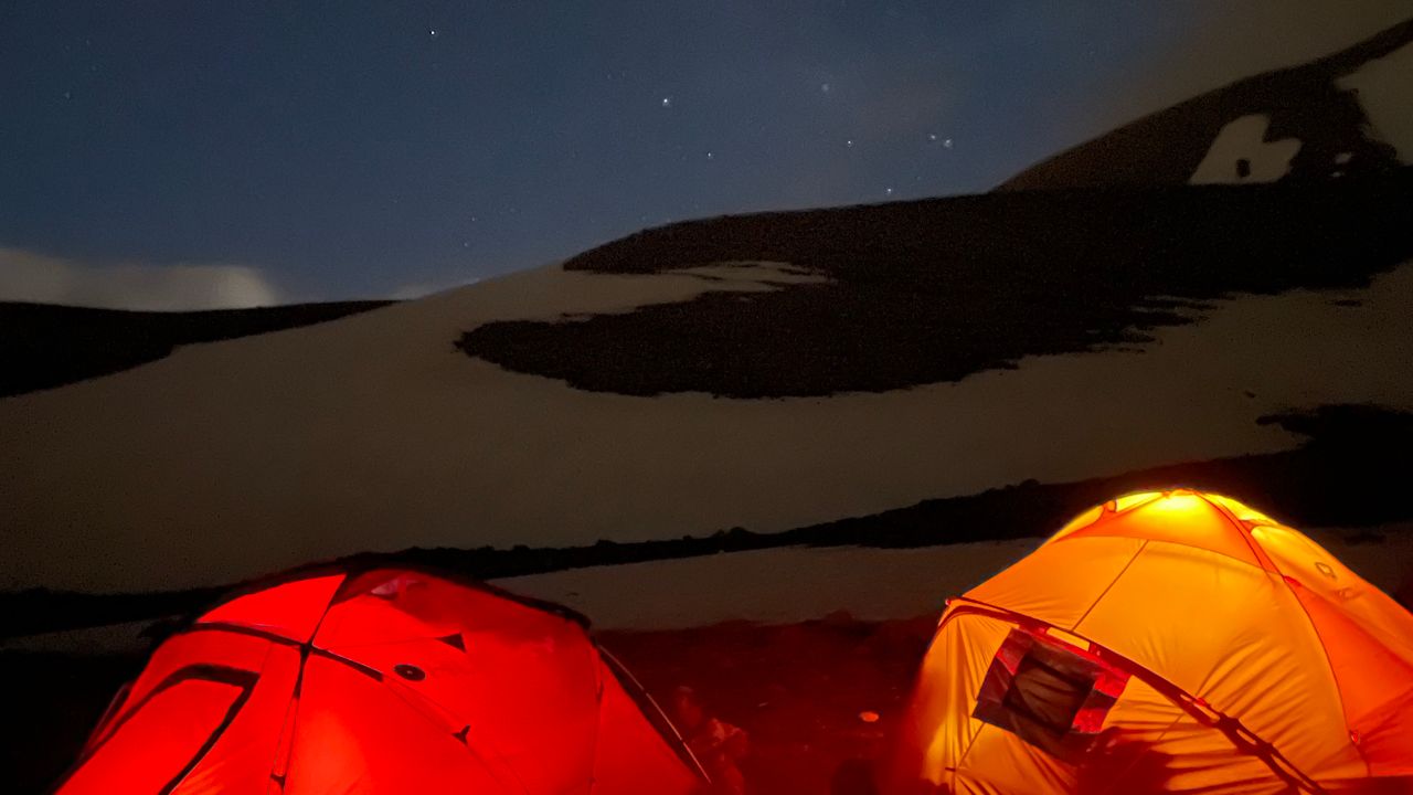 Barracas de camping iluminadas sob a neve em uma noite de montanha
