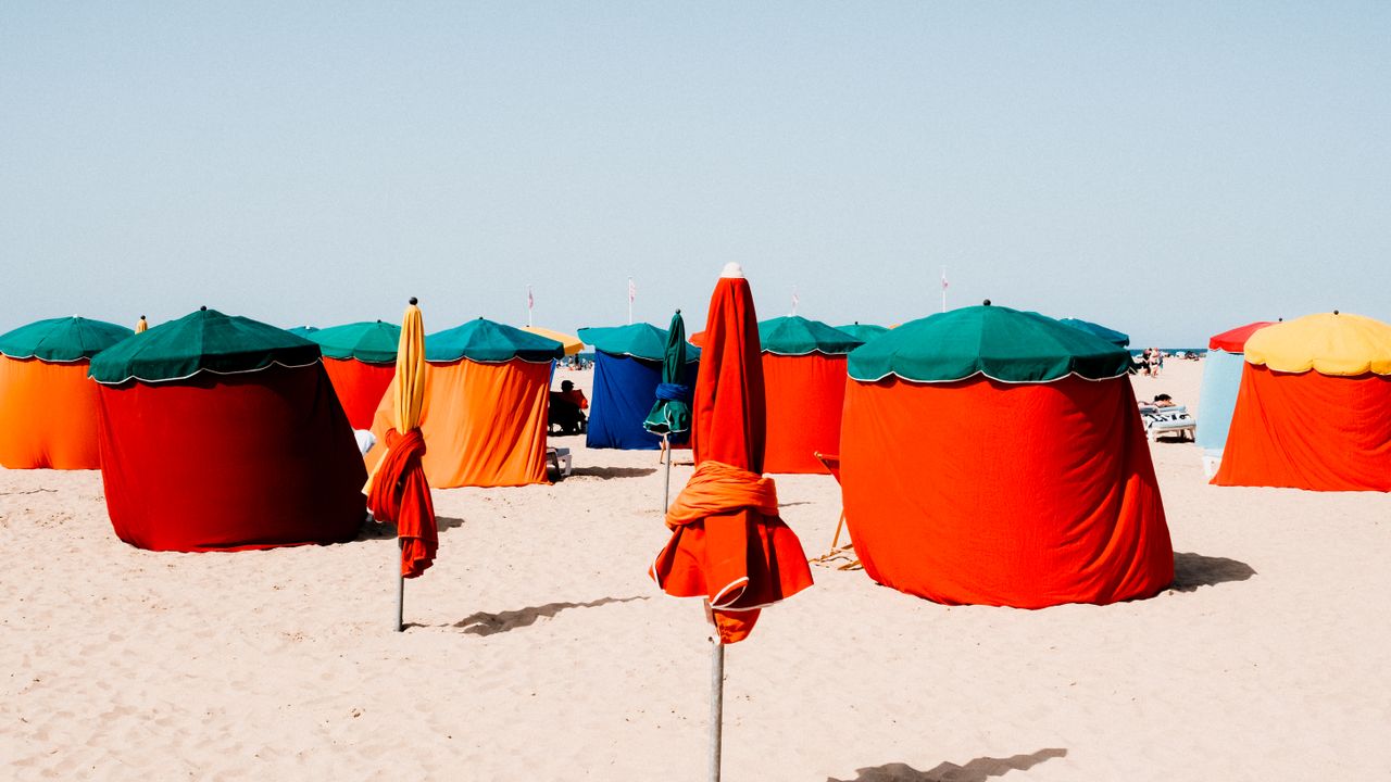Tendas e abrigos coloridos montados na areia de uma praia ensolarada