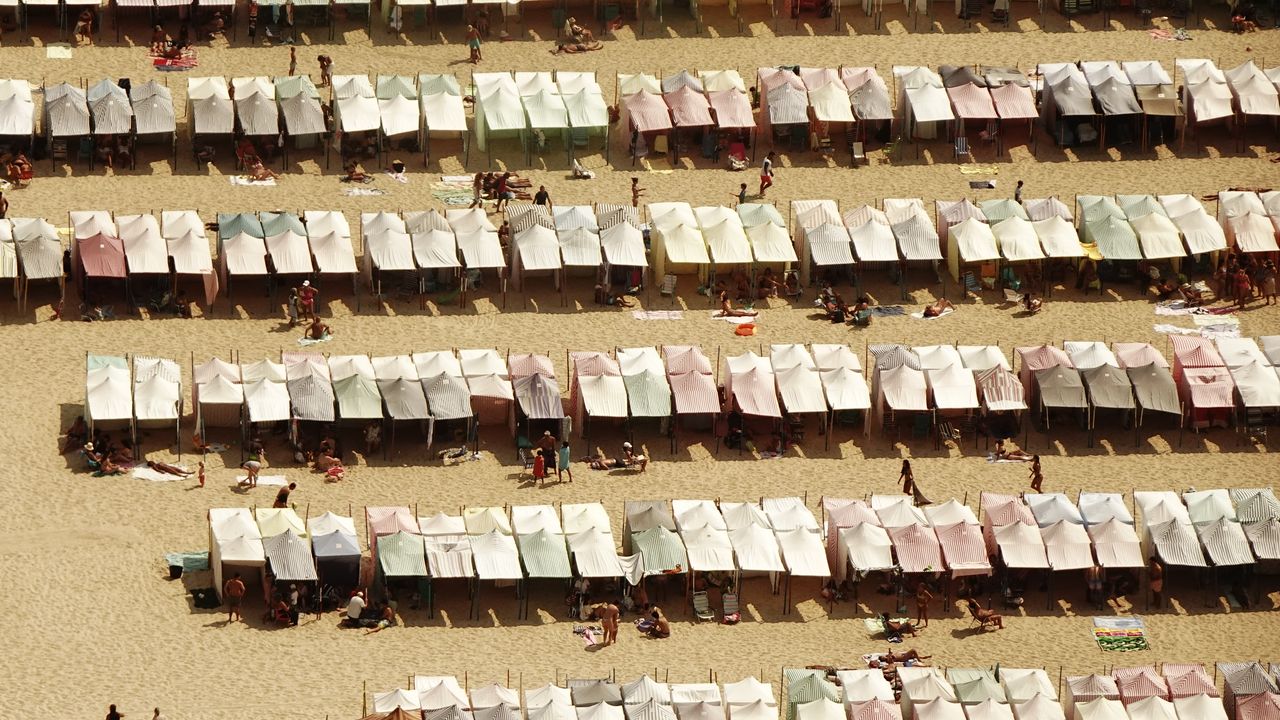 Barracas e tendas coloridas montadas na areia de uma praia ensolarada
