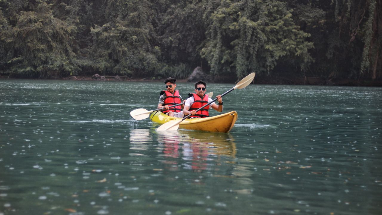 Duas pessoas remando em um caiaque inflável em um lago calmo