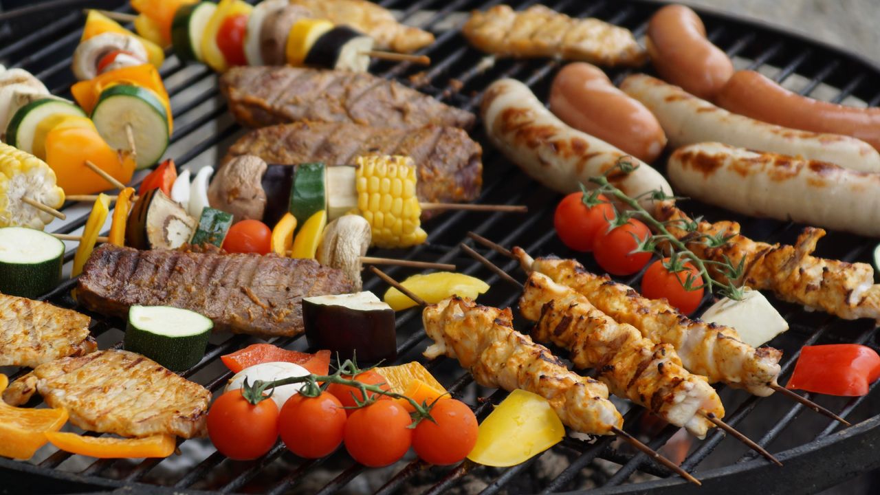 Carne e legumes grelhando sobre carvão em uma churrasqueira