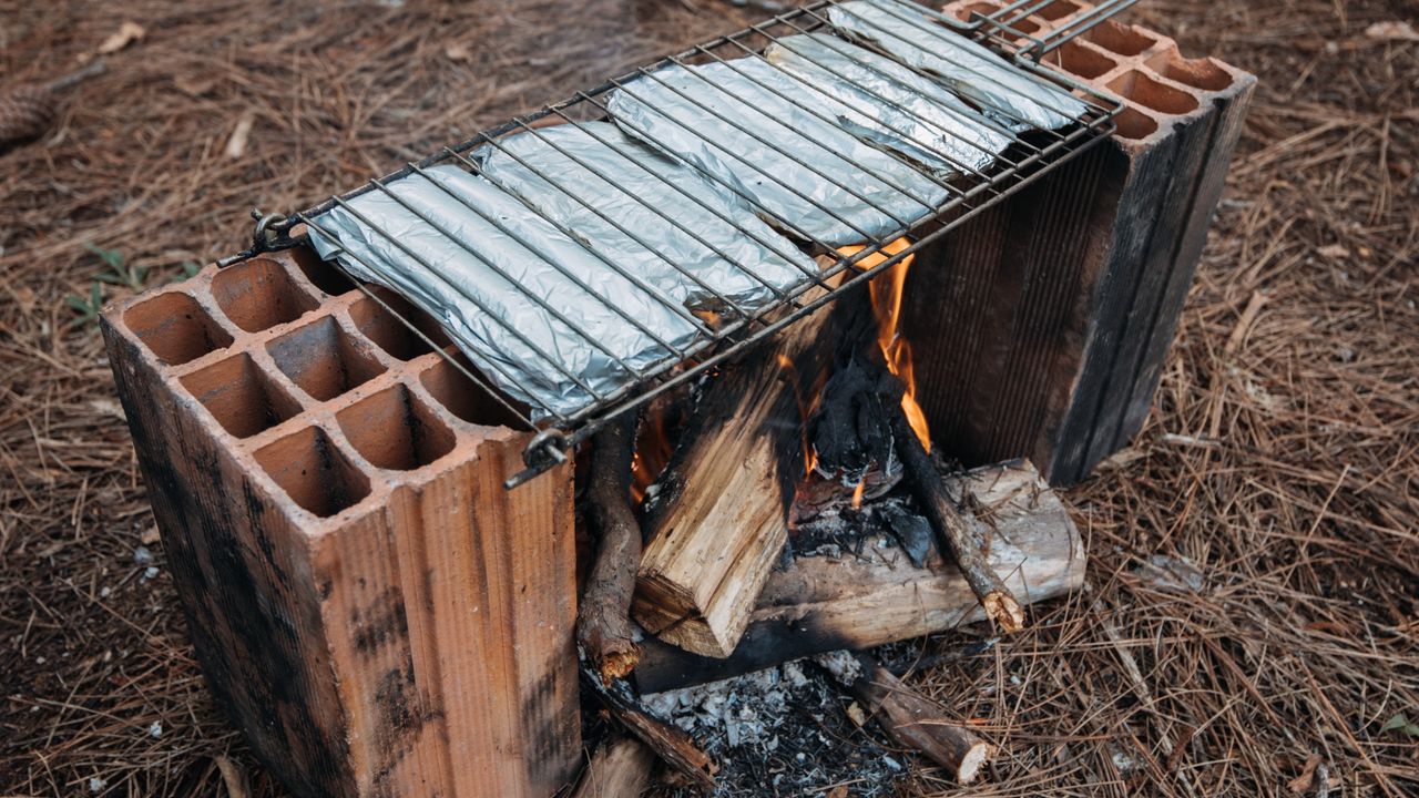 Churrasco feito em uma grelha rústica apoiada sobre tijolos