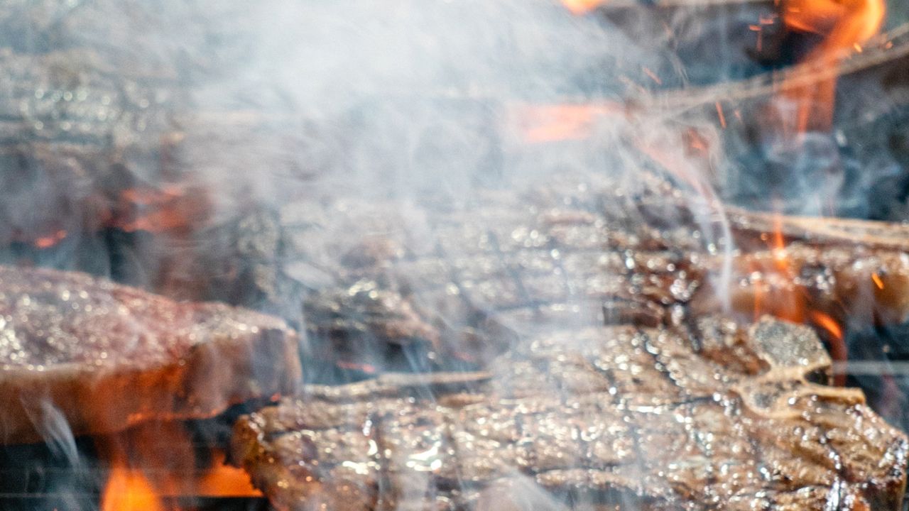 Carnes grelhando em uma churrasqueira na varanda