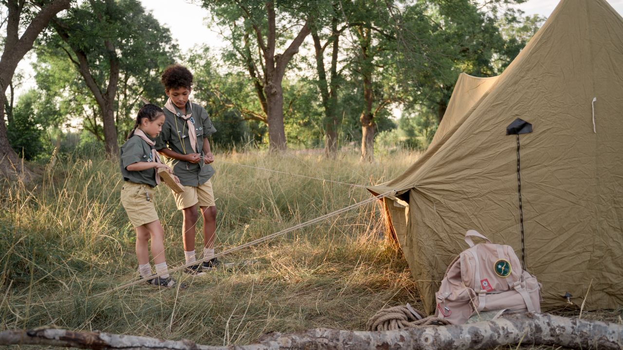 Crianças montando uma barraca de acampamento ao ar livre