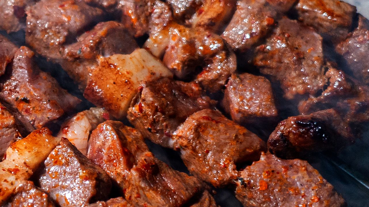 Espetos de carne girando sobre a brasa em uma churrasqueira