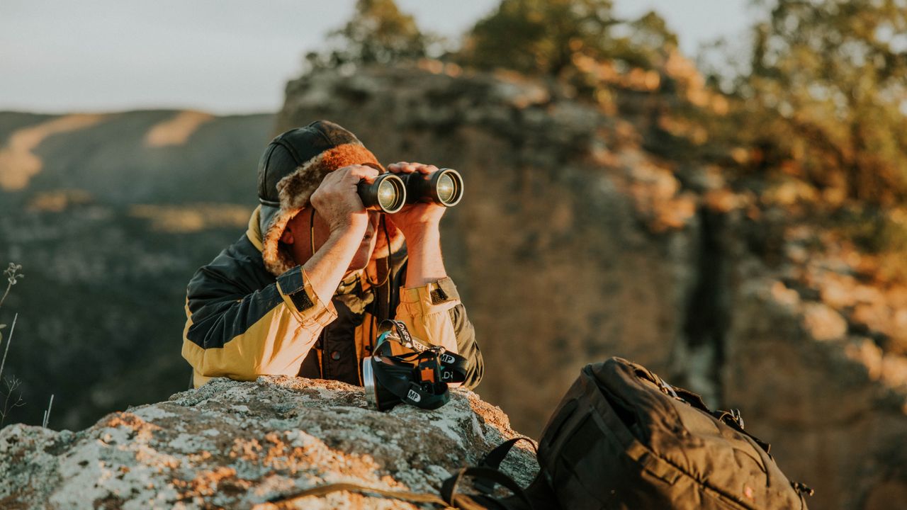 Observador usando binóculo para acompanhar a vida selvagem em uma paisagem natural