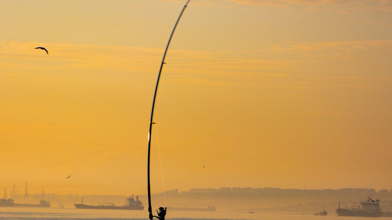 Pescador arremessando a vara no mar durante a pesca de praia